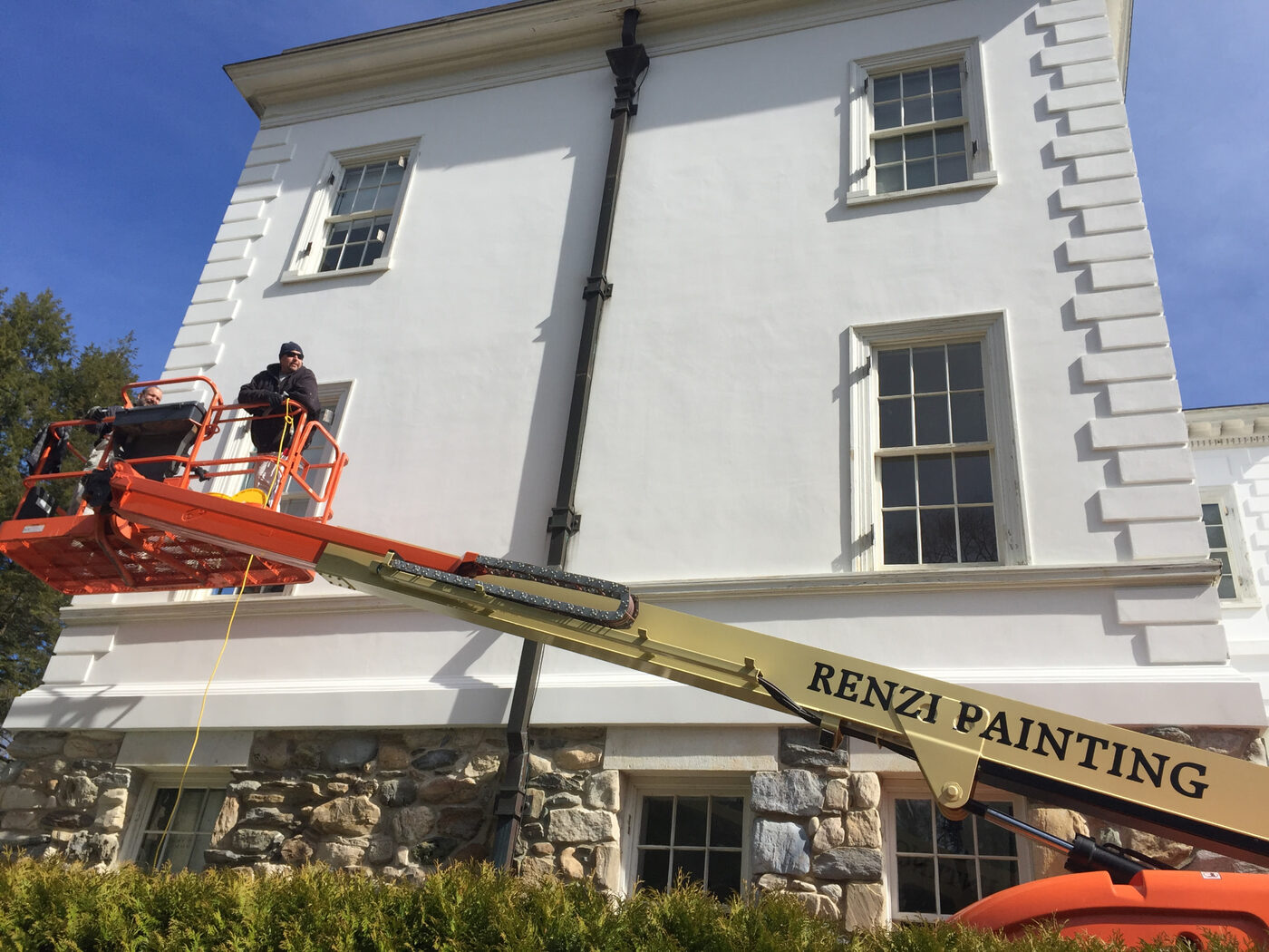 Renzi Painting crew on a lift restoring the white exterior of The Mount estate in Lenox, Massachusetts